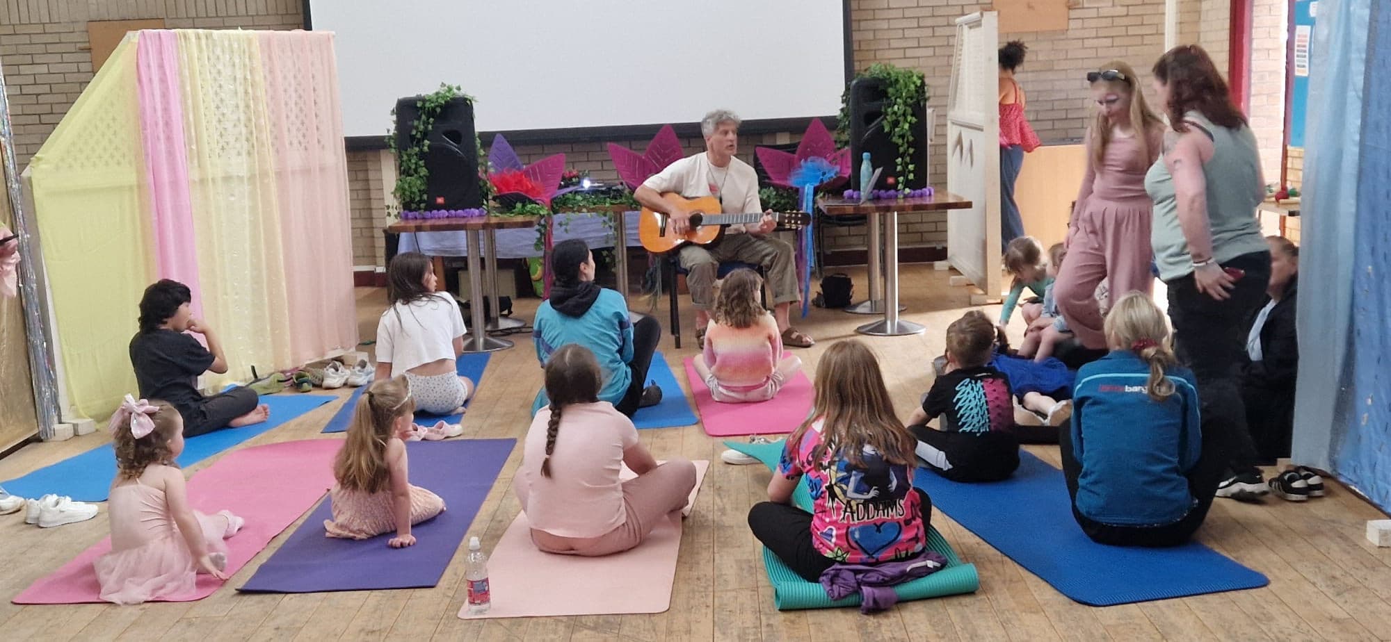Families on yoga mats for a gentle song together.